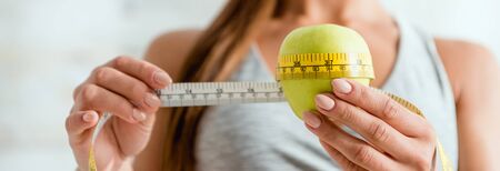 panoramic shot of young woman measuring green apple