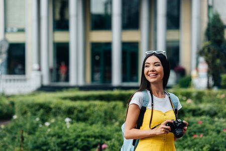 attractive and asian woman with digital camera looking away