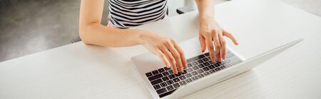 panoramic shot of girl in striped t-shirt using laptop at home