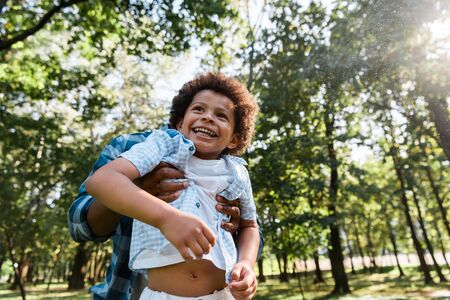 cropped view of father holding in arms adorable african american son