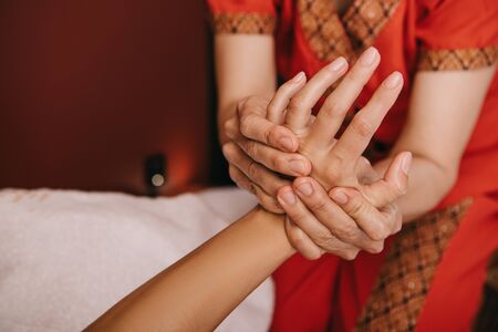 cropped view of masseur doing hand massage to woman in spa salonの写真素材