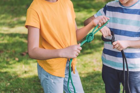 cropped view of kids holding ropes with sea knots outside