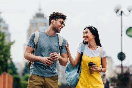 handsome man and asian woman smiling and holding paper cupsの写真素材