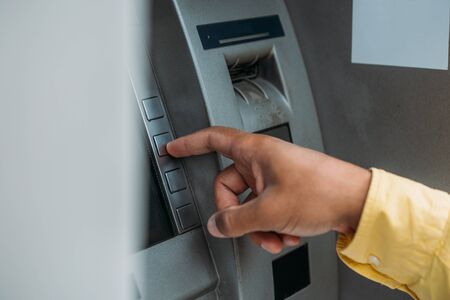cropped view of bi-racial man pressing button on atm machine