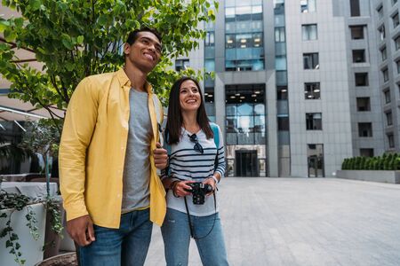 happy woman and mixed race man standing near building