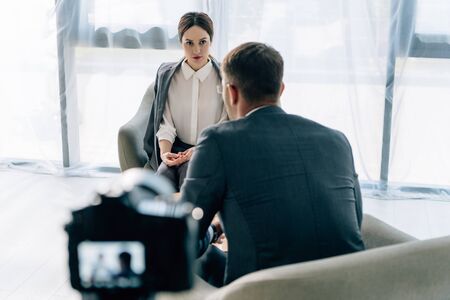 selective focus of attractive journalist talking with businessman in formal wearの写真素材