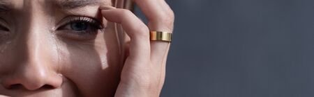 panoramic shot of crying woman in ring isolated on grey