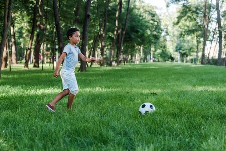 adorable african american child playing football on green grassの写真素材