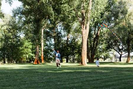 happy african american son and father running on grass in parkの写真素材
