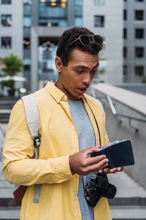 surprised mixed race man looking at wallet with money