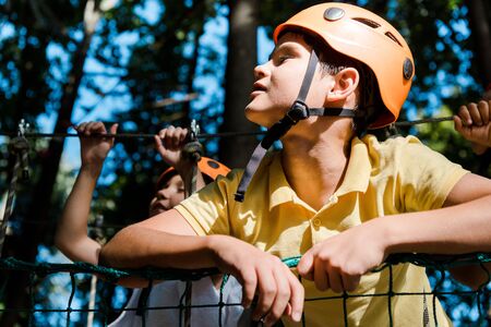 selective focus of cute boy in orange helmet near friends