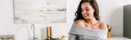 panoramic shot of happy woman smiling in kitchenの写真素材