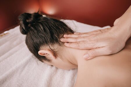 cropped view of masseur doing neck massage to woman in spa salonの写真素材