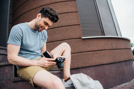 smiling and handsome man in glasses looking at digital camera