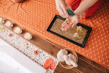 cropped view of masseur pouring fragrance oil on handの写真素材