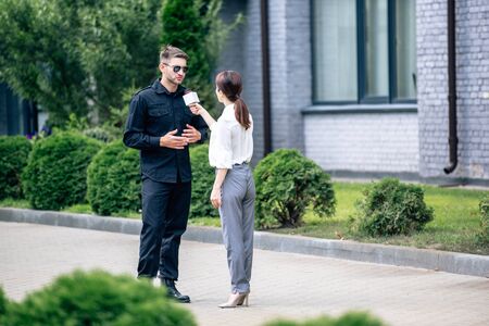 journalist holding microphone and talking with handsome policeman in uniform