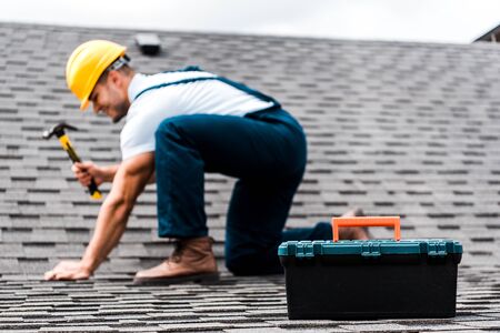 selective focus of toolbox near repairman holding hammer on rooftopの写真素材