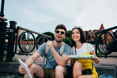 smiling and handsome man holding digital tablet and asian woman holding mapの写真素材