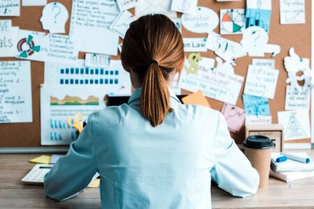 back view of woman sitting at desk near notice board with lettersの写真素材