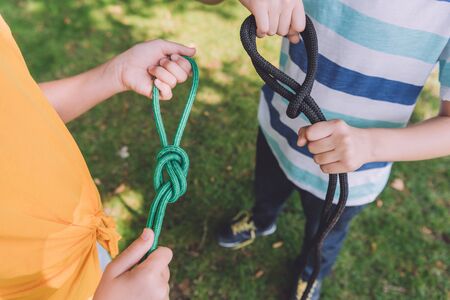 cropped view of kids holding ropes outsideの写真素材