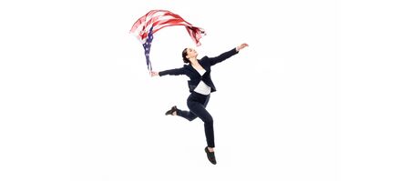 panoramic shot of businesswoman dancing with usa national flag isolated on whiteの写真素材
