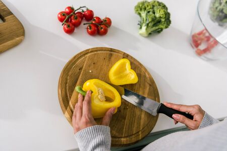top view of woman holding knife near cutting board with paprikaの写真素材