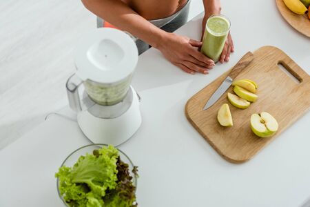 cropped view of girl holding glass with smoothie on tableの写真素材