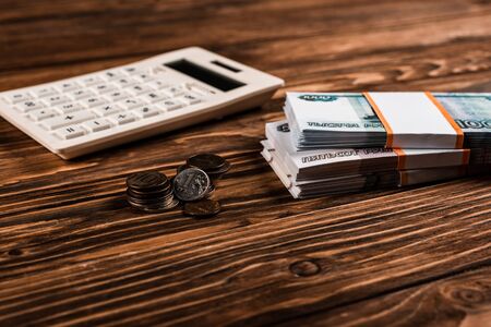 selective focus of white calculator near russian money and coins on wooden tableの写真素材
