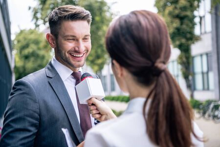 journalist holding microphone and talking with businessman in formal wearの写真素材