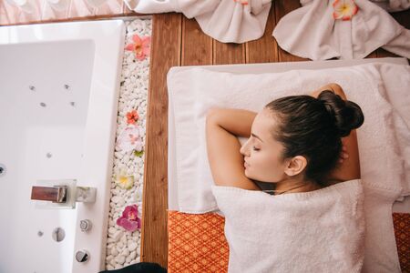 top view of attractive woman with closed eyes lying on massage matの写真素材