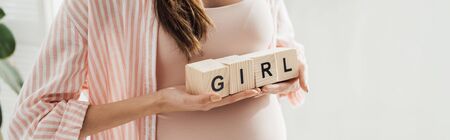 panoramic shot of pregnant woman holding wooden blocks with word girlの写真素材