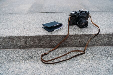 black wallet with cash near digital camera on stairs