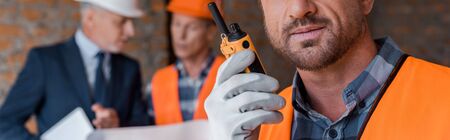 panoramic shot of bearded man holding walkie talkie