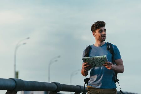 handsome man in t-shirt holding map and looking away