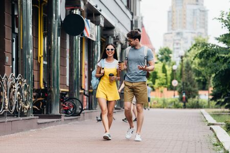 handsome man and asian woman talking and holding paper cups