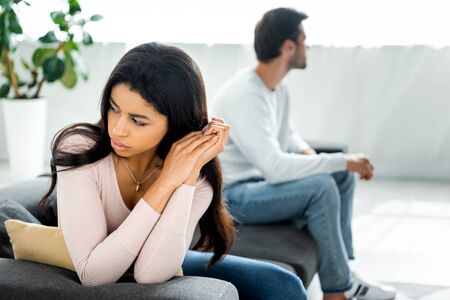 selective focus of sad african american woman sitting on sofa