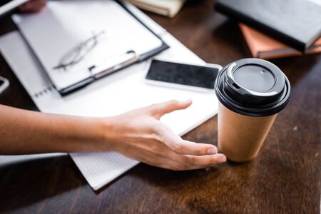 cropped view of student taking paper cup on tableの写真素材