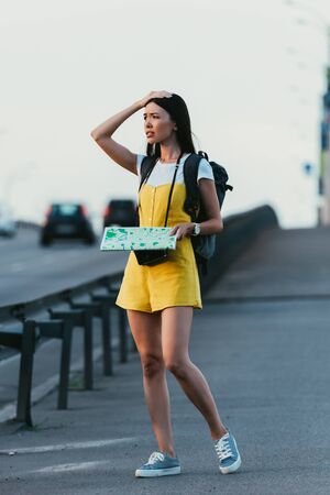 worried  and asian woman in overalls holding map and looking awayの写真素材