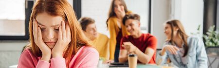 panoramic shot of schoolchildren laughing while bullying sad girl on foreground