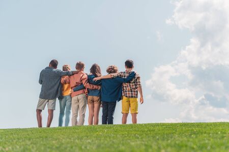 selective focus of multicultural kids standing and hugging in park