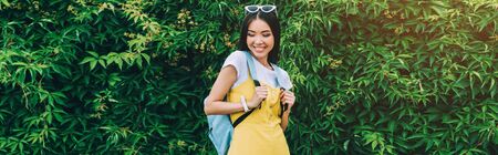 panoramic shot of asian and attractive woman smiling and looking down