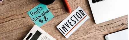 panoramic shot of blue sticky note with lettering near calculator and laptopの写真素材