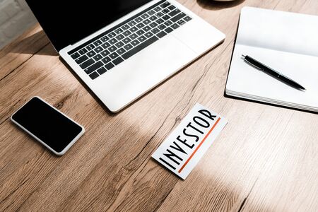 paper with investor lettering near gadgets on tableの写真素材