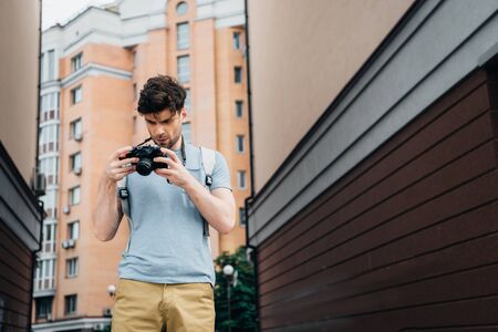 handsome man in t-shirt and shorts looking at digital camera