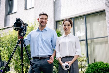 attractive journalist holding microphone and cameraman holding digital video camera