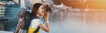 side view of asian woman with backpack taking photoの写真素材