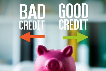 pink piggy bank on wooden desk near bad credit, good credit lettering in office の写真素材