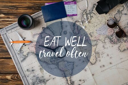 top view of magnifying glass, small model plane, sunglasses, photo camera, lens and passport with boarding pass on map with eat well, travel often illustrationの写真素材