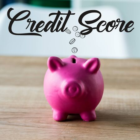 toy piggy bank on wooden desk near credit score lettering in office の写真素材