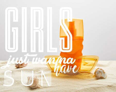 yellow stylish sunglasses and sunscreen in orange bottle on sand with seashells on grey background with girls just wanna have sun illustrationの写真素材